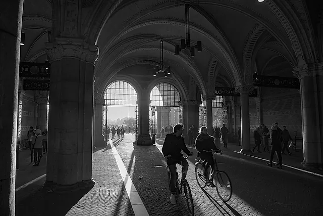 The passage under the Rijksmuseum, with stone vaults and a cyclist riding through the cycle lane (black and white)
